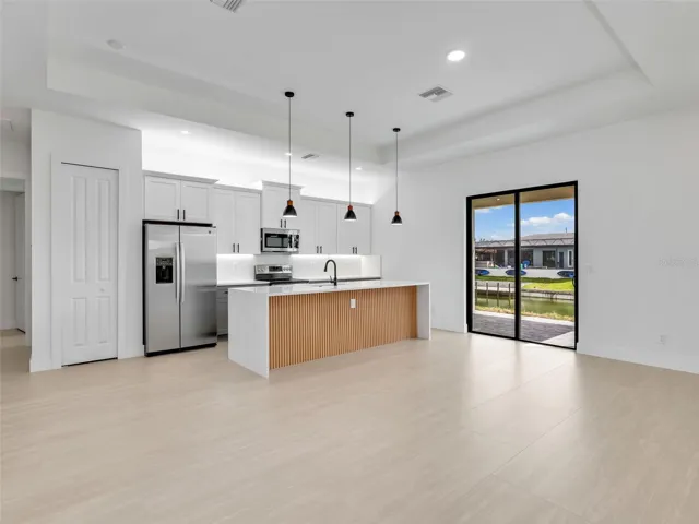 Kitchen with open floor plan, stainless steelappliances, hanging light fixtures, a trayceiling, and white cabinets