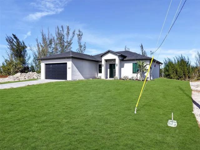 View of front of home featuring driveway, afront lawn, stucco siding, a garage, and a shingled roof