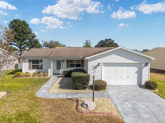 Front Exterior Daylight – Bright and well-maintained exterior with vinyl siding, mature shrubs, and a color-coated concrete walkway and drive for a clean, inviting look.