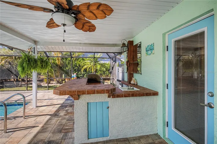Spacious covered patio on pool deck with outdoor kitchen with pool access bath