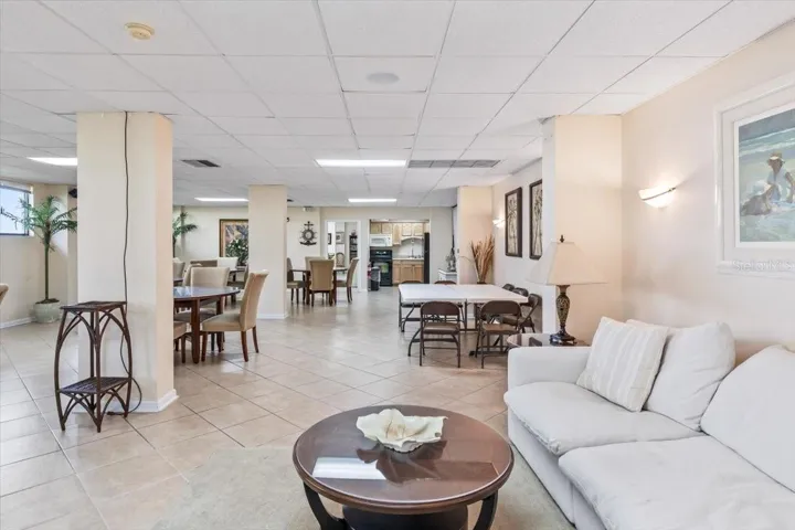 Bright and welcoming community room with an open layout, tile flooring, and flexible seating for gatherings, games, or meetings. Coastal décor and an adjoining kitchen make it perfect for social events and relaxed resident enjoyment.