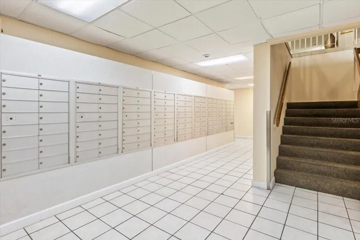 Secure and well-maintained lobby mail area featuring individual resident mailboxes, bright lighting, tiled flooring, and convenient stair access. Clean, organized, and easily accessible for daily use.
