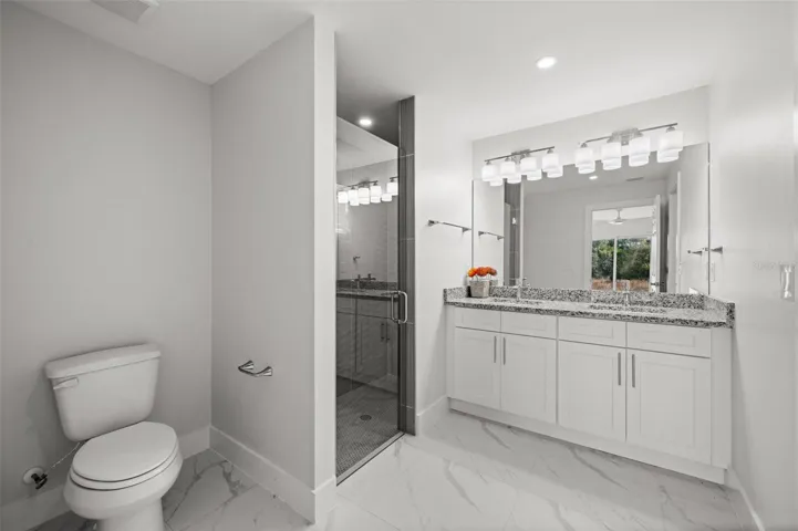 Dual Quartz Vanities With Glass-Enclosed Walk-In Shower