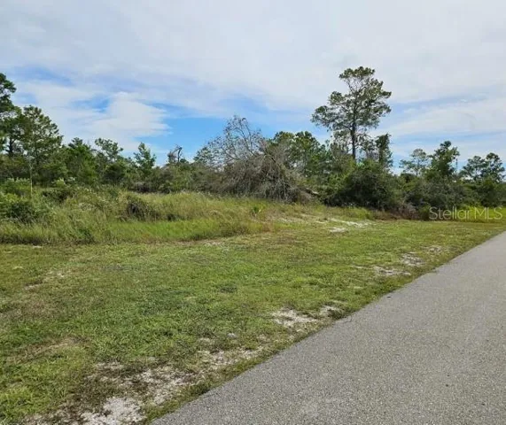 Lot for sale on a paved road, house nearby.