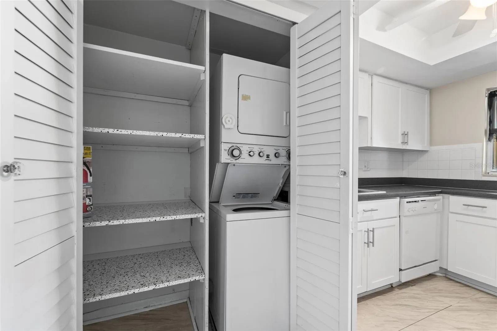 Kitchen storage and a view of the stackable washer and dryer