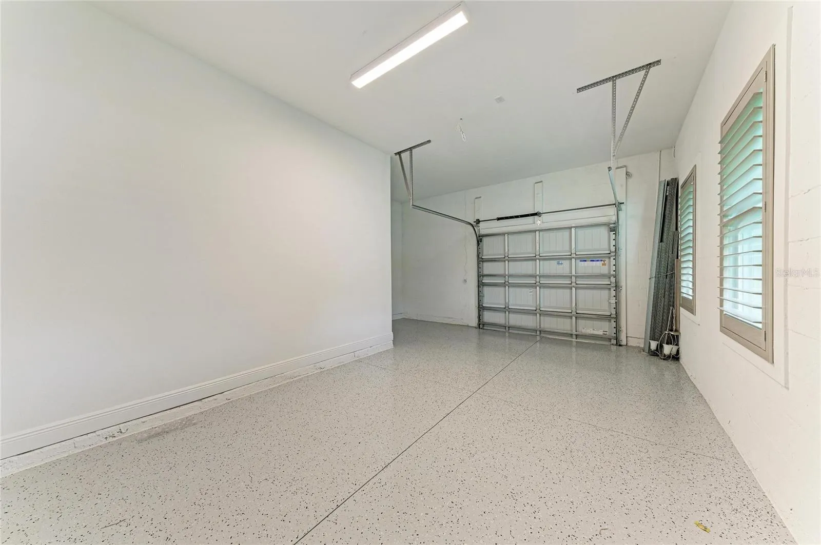 Spacious garage featuring epoxy-coated flooring and ample storage