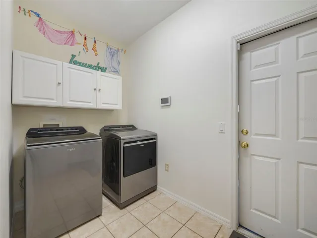 A SPACIOUS LAUNDRY ROOM just off the kitchen features cabinetry and a folding counter for added convenience.