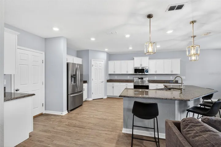 Kitchen features granite counter tops, upgraded pendant lighting highlights the breakfast bar, stainless steel appliances and white cabinetry with crown molding.