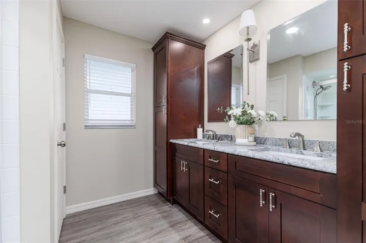 En Suite Primary Bath with dual sinks, stone countertops, plenty of storage, and great lighting