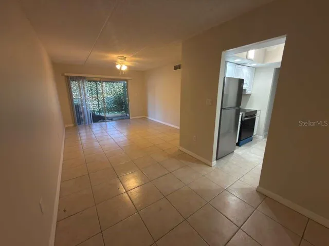 Bright and spacious living and dining area with tile flooring and sliding glass doors opening to the private patio.