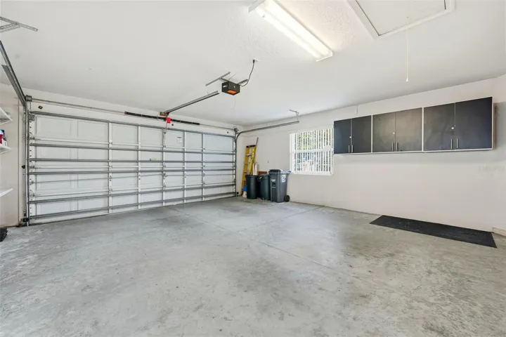 2-car garage with extra storage cabinets, shelving and pull down stairs for attic access