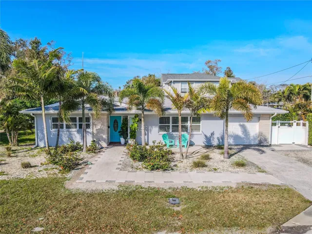 Single-story ranch style home featuring a clean, coastal-inspired façade with smooth stucco finish and contrasting stone accents. A welcoming covered front entry provides sheltered access, while multiple front-facing windows enhance curb appeal and allow for abundant natural light inside.