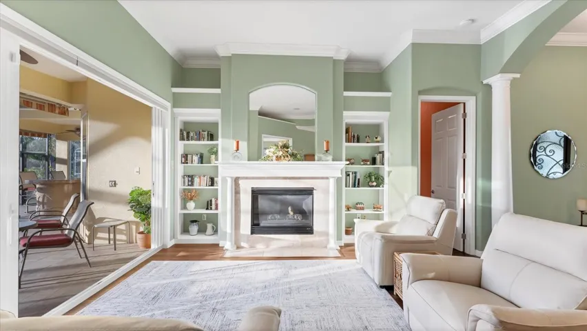Sliders open, soft Florida air drifting in, and the warm glow of the gas fireplace setting the tone = seamless indoor and outdoor living.