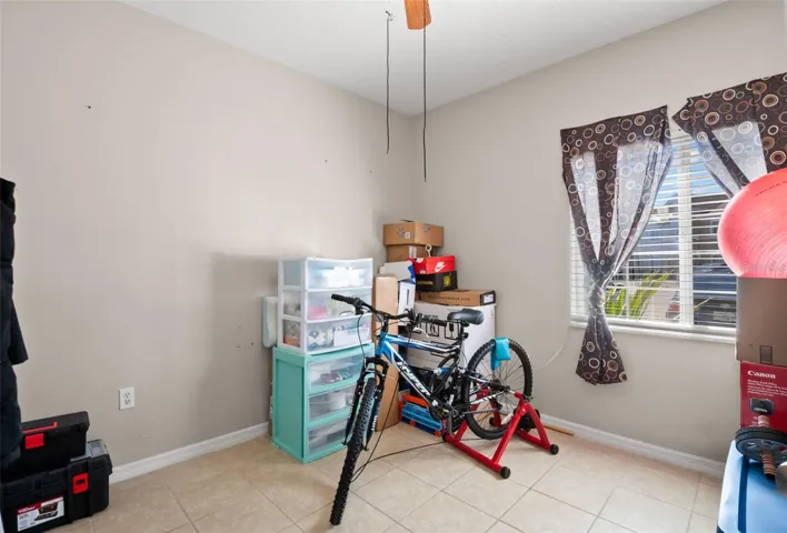 Versatile third bedroom featuring ceramic tile flooring, a large window for natural light, and a neutral color palette. Ideal for use as a guest room, home office, fitness space, or hobby room, offering flexibility to suit a variety of lifestyle needs.