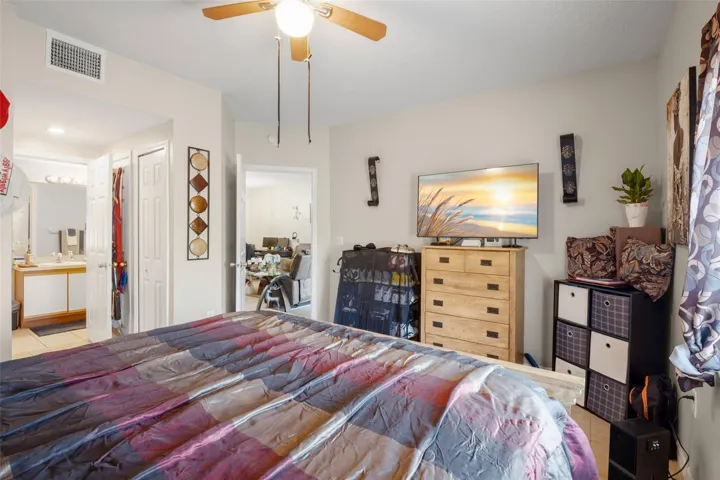 Spacious primary suite featuring ceramic tile flooring and a functional layout with direct access to the en suite bath and walk-in closet. The neutral color palette and ceiling fan enhance comfort, while the split-bedroom floor plan provides added privacy from the secondary bedrooms. Ample wall space allows for flexible furniture placement and storage solutions.