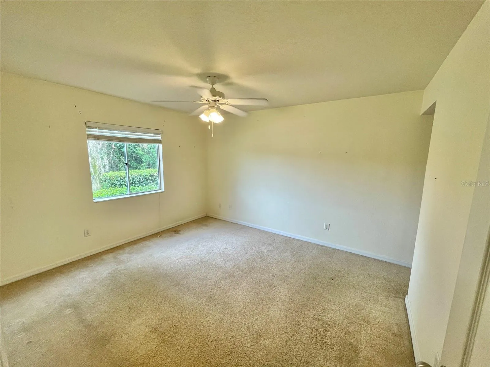 unstaged primary bedroom with lake view, en-suite bathroom, walk in closet and ceiling fan