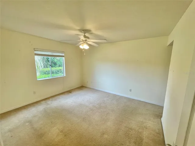 unstaged primary bedroom with lake view, en-suite bathroom, walk in closet and ceiling fan