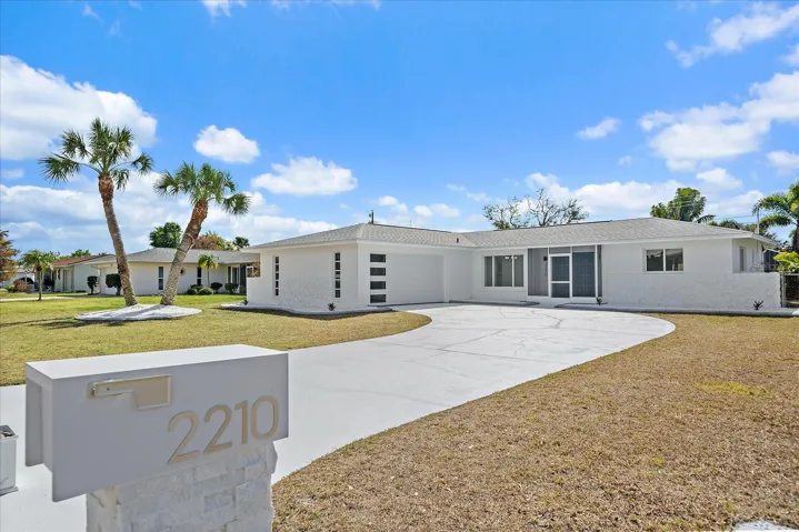 Front view of house with expansive driveway and modern mailbox with address numbers and stone accents.