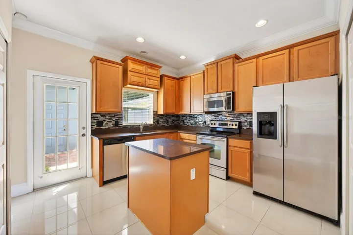 The OPEN LIVING & DINING areas create an easy everyday flow, while the spacious kitchen offers ample storage, STAINLESS STEEL APPLIANCES, a tiled backsplash, and a prep ISLAND with additional cabinetry and workspace.