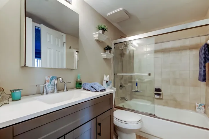 Jack and Jill bathroom that leads to Bedroom 2 and hallway has tub/shower, new slider glass door, and new vanity.