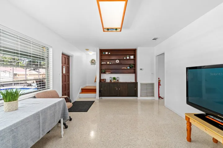 Living Room has built-in shelving and overlooks the pool through a large window.