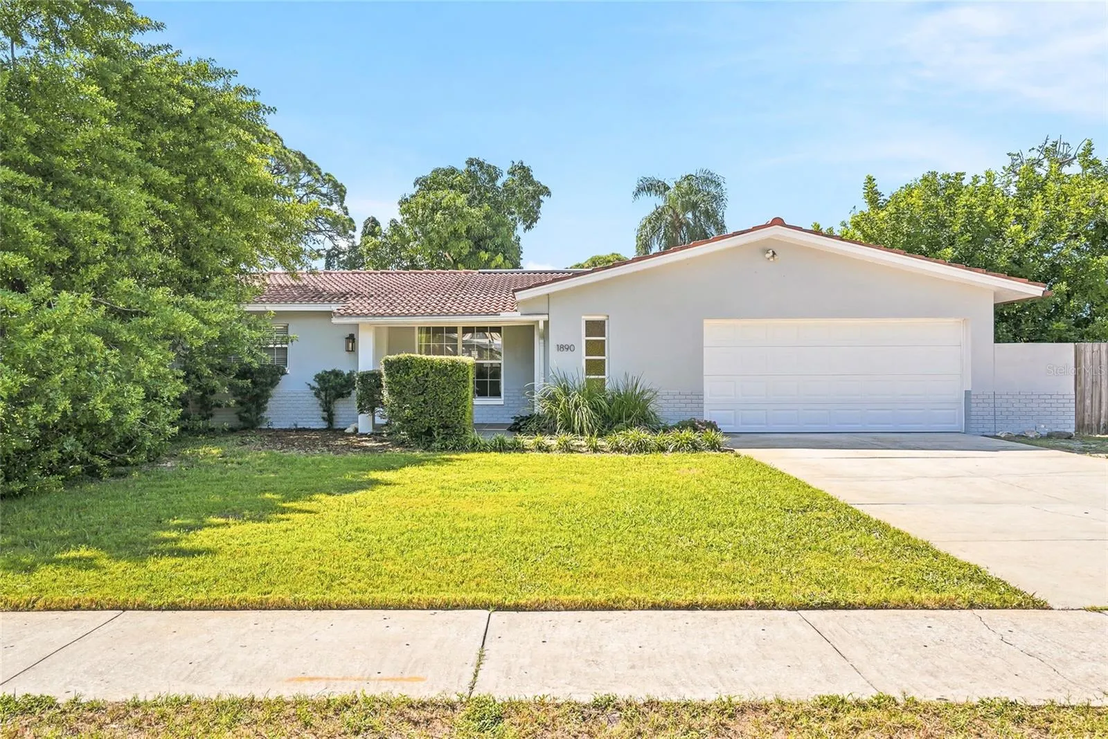 A welcoming first impression with a broad front lawn, mature landscaping, and a tile roof that adds distinctive Florida character.