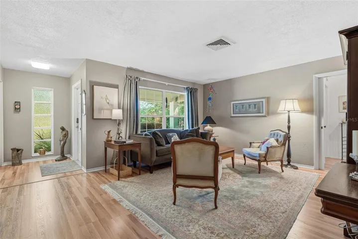 Natural light and garden views bring warmth to the front living room, creating an inviting setting for conversation or a quiet afternoon.