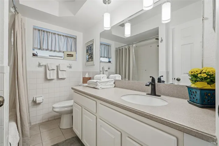 A generous vanity, broad mirror, and pendant lighting create a bright, comfortable space to get ready, with cabinet storage below.