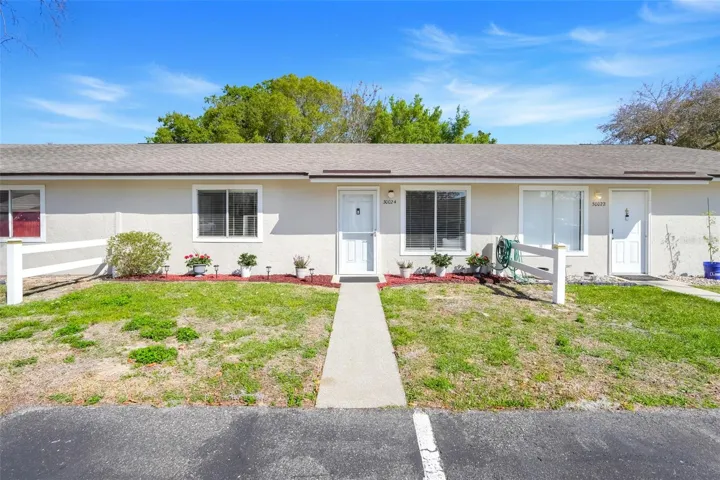 Welcoming front entrance with beautifully maintained flower beds, plus one designated parking space and adjacent guest parking.