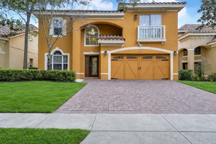 A brick paver driveway leading to a spacious two-car garage with decorative carriage-style doors and black hardware accents.
