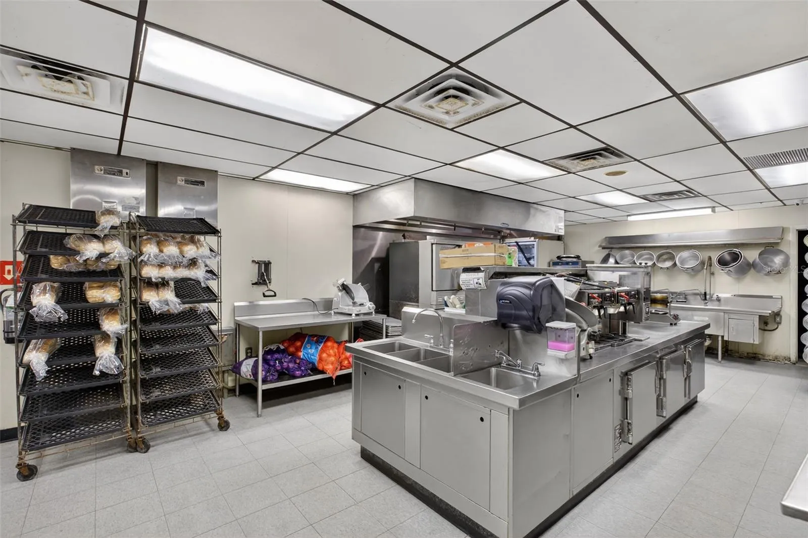 Fully equipped commercial kitchen infrastructure including hood system, fryers, ranges, griddles, and prep stations.