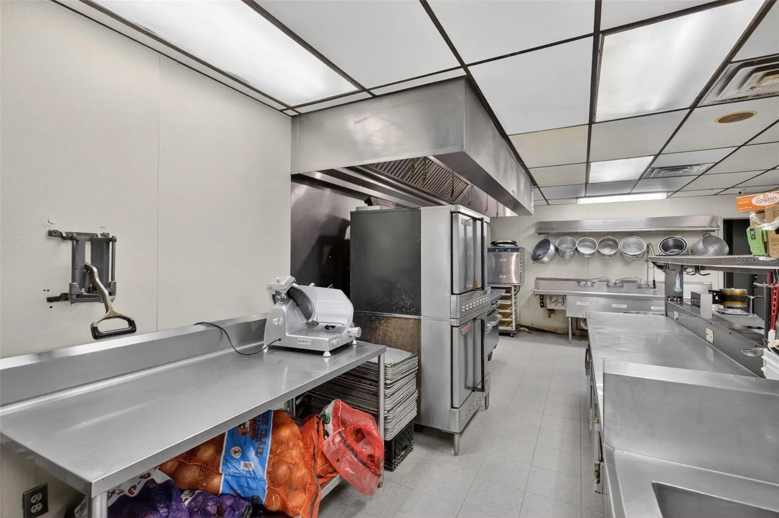 Fully equipped commercial kitchen infrastructure including hood system, fryers, ranges, griddles, and prep stations.