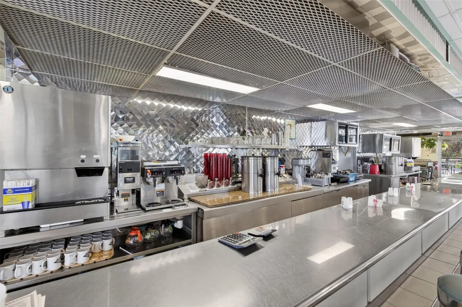 Fully equipped commercial kitchen infrastructure including hood system, fryers, ranges, griddles, and prep stations.