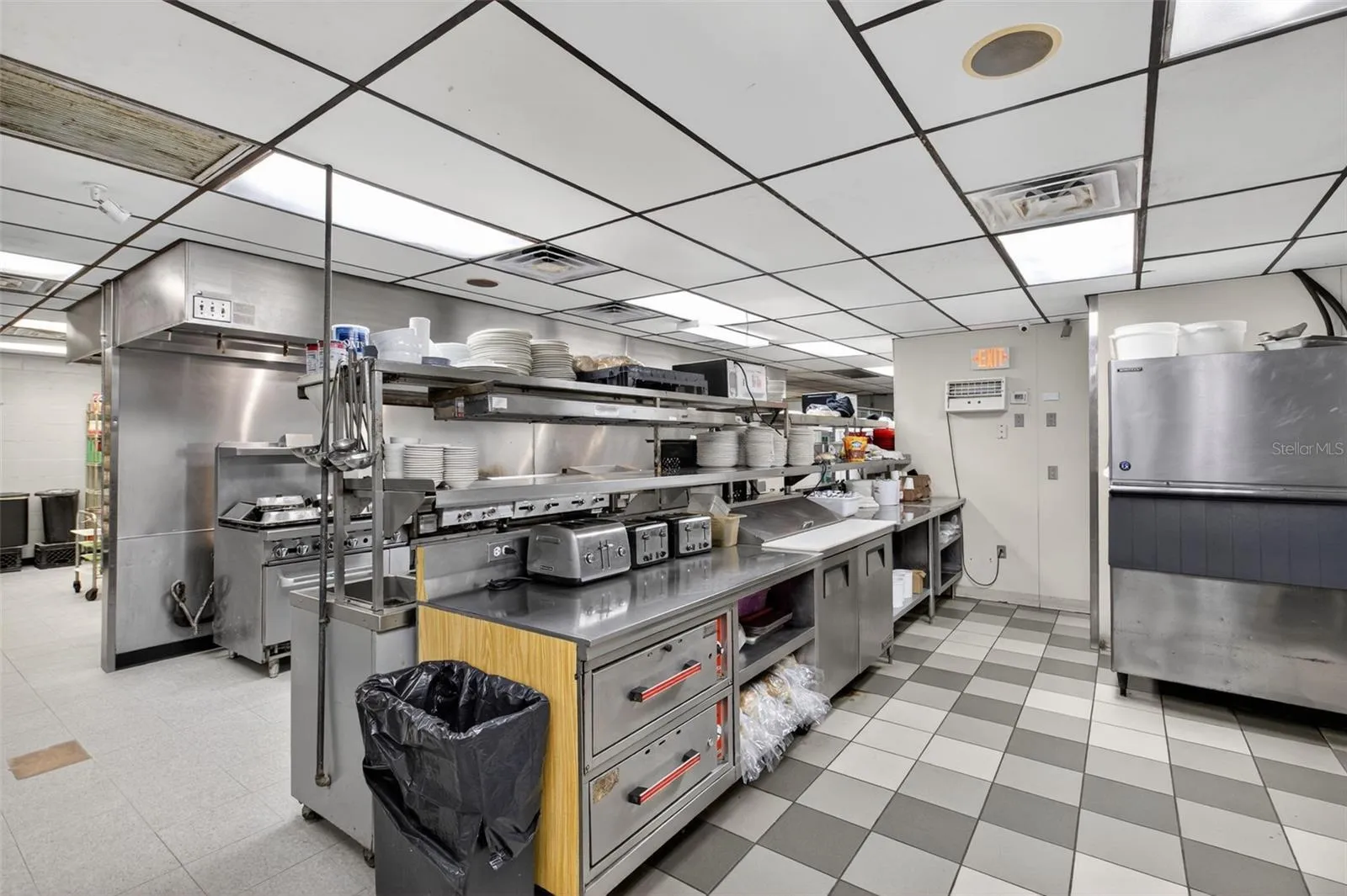 Fully equipped commercial kitchen infrastructure including hood system, fryers, ranges, griddles, and prep stations.