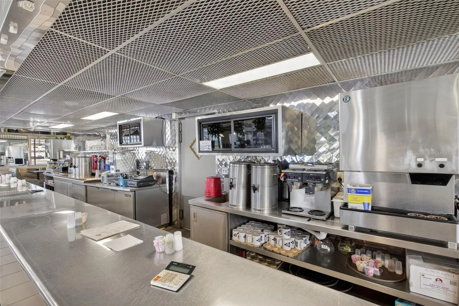 Fully equipped commercial kitchen infrastructure including hood system, fryers, ranges, griddles, and prep stations.