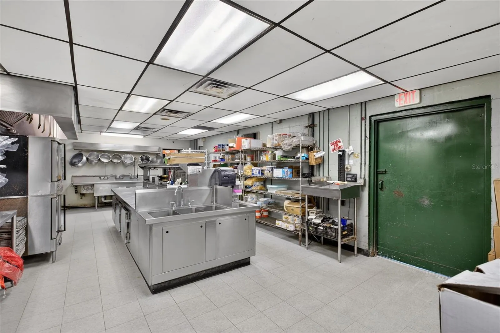 Fully equipped commercial kitchen infrastructure including hood system, fryers, ranges, griddles, and prep stations.