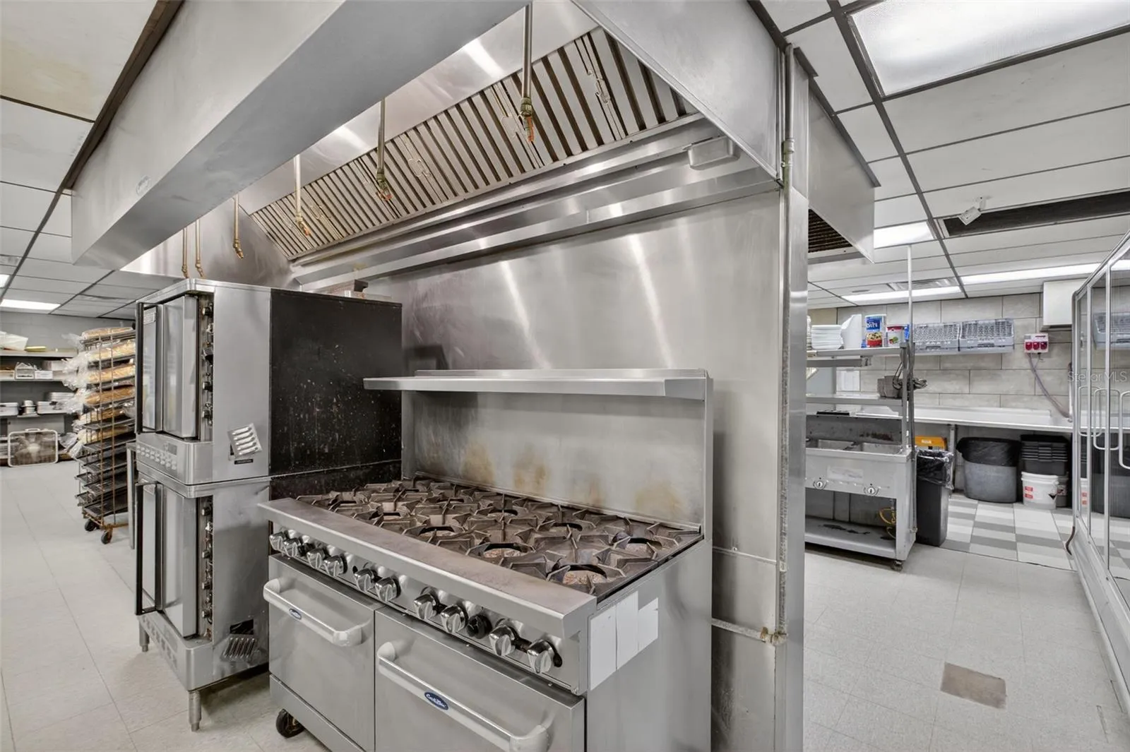 Fully equipped commercial kitchen infrastructure including hood system, fryers, ranges, griddles, and prep stations.