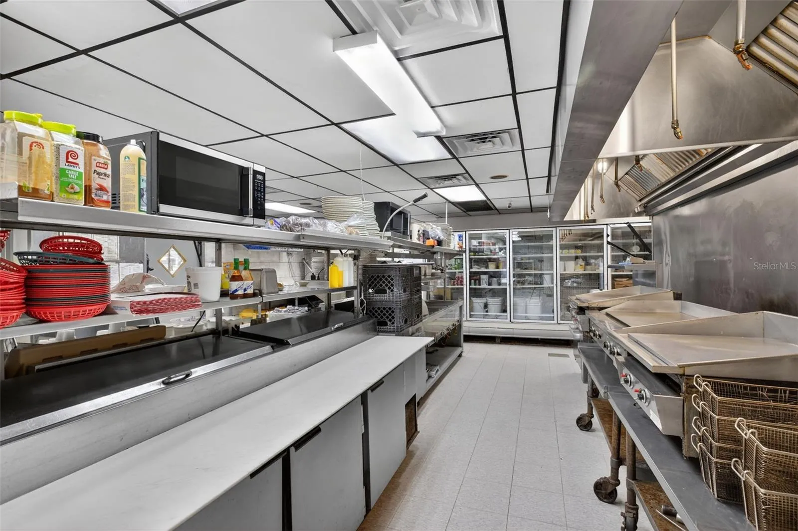 Fully equipped commercial kitchen infrastructure including hood system, fryers, ranges, griddles, and prep stations.