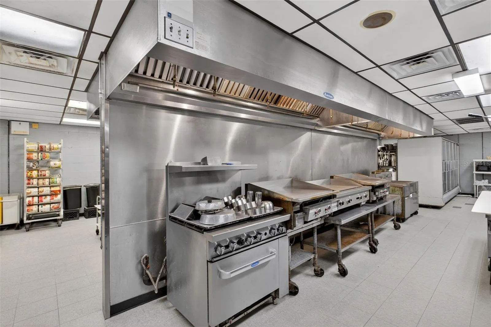 Fully equipped commercial kitchen infrastructure including hood system, fryers, ranges, griddles, and prep stations.