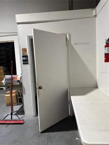 View of private restroom in warehouse with an outside sink.