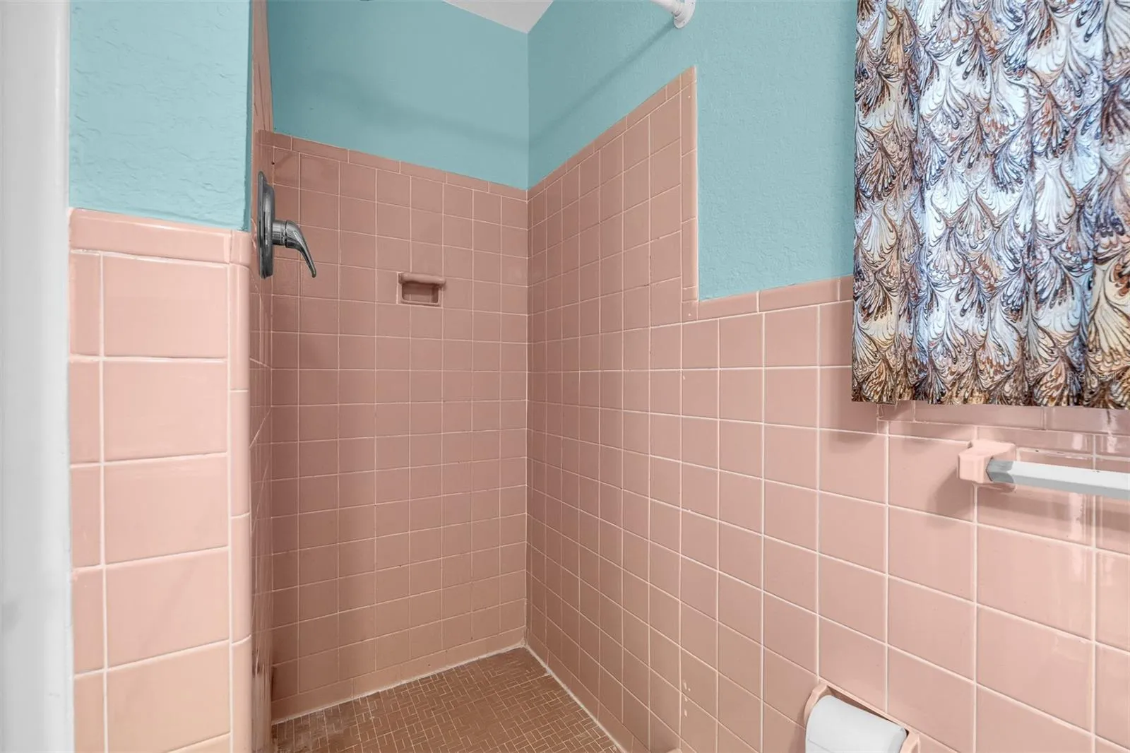Shower area with vintage tile surround, built-in soap ledge, and overhead fixture.