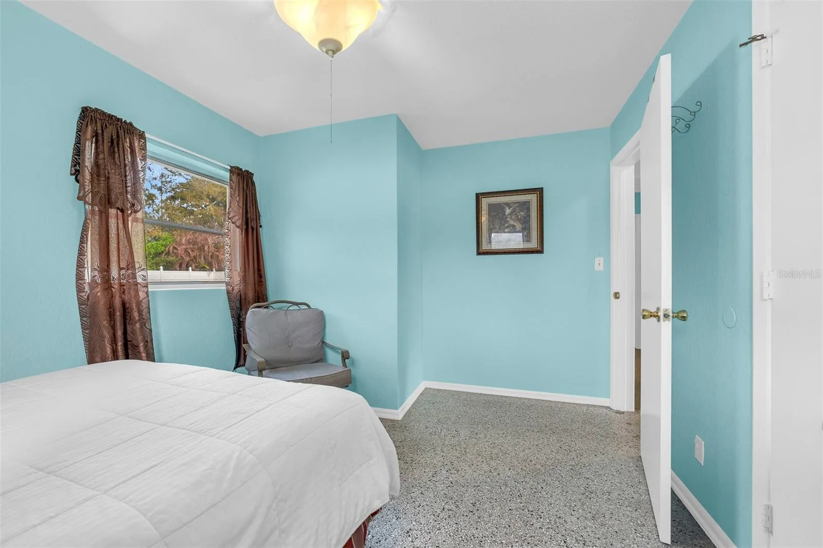 Bedroom angle showing seating, wall décor, and hallway access.