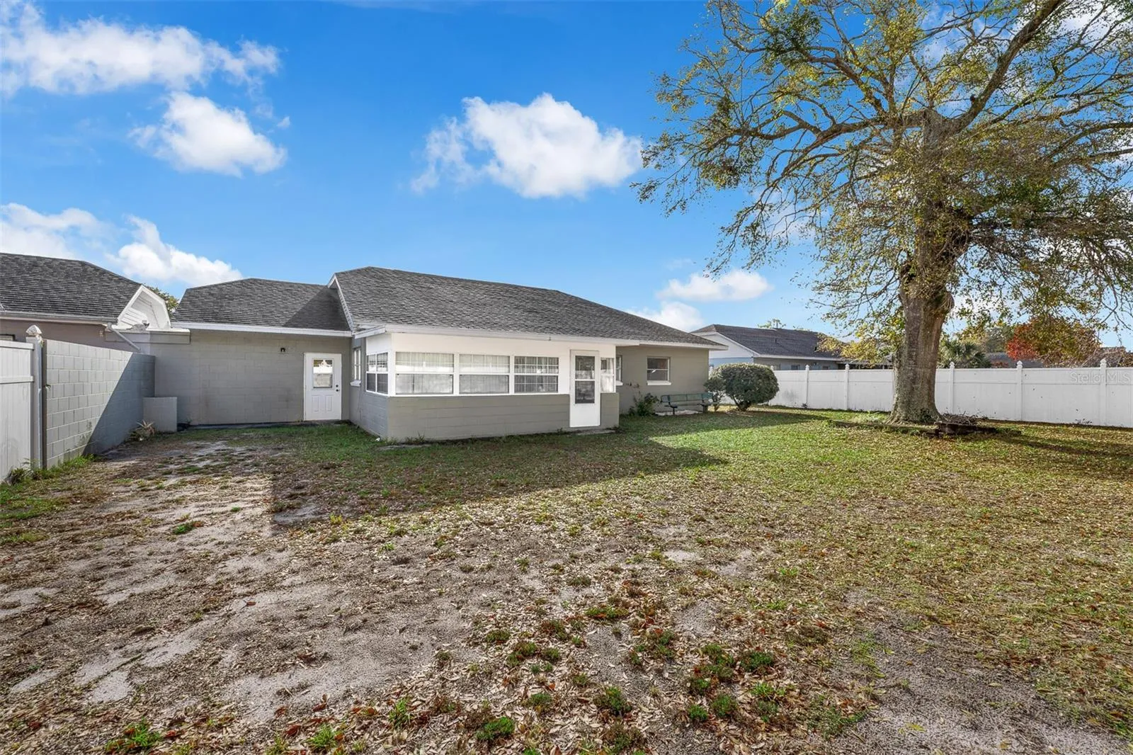 Backyard with vinyl privacy fence, shade tree, and access to sunroom.