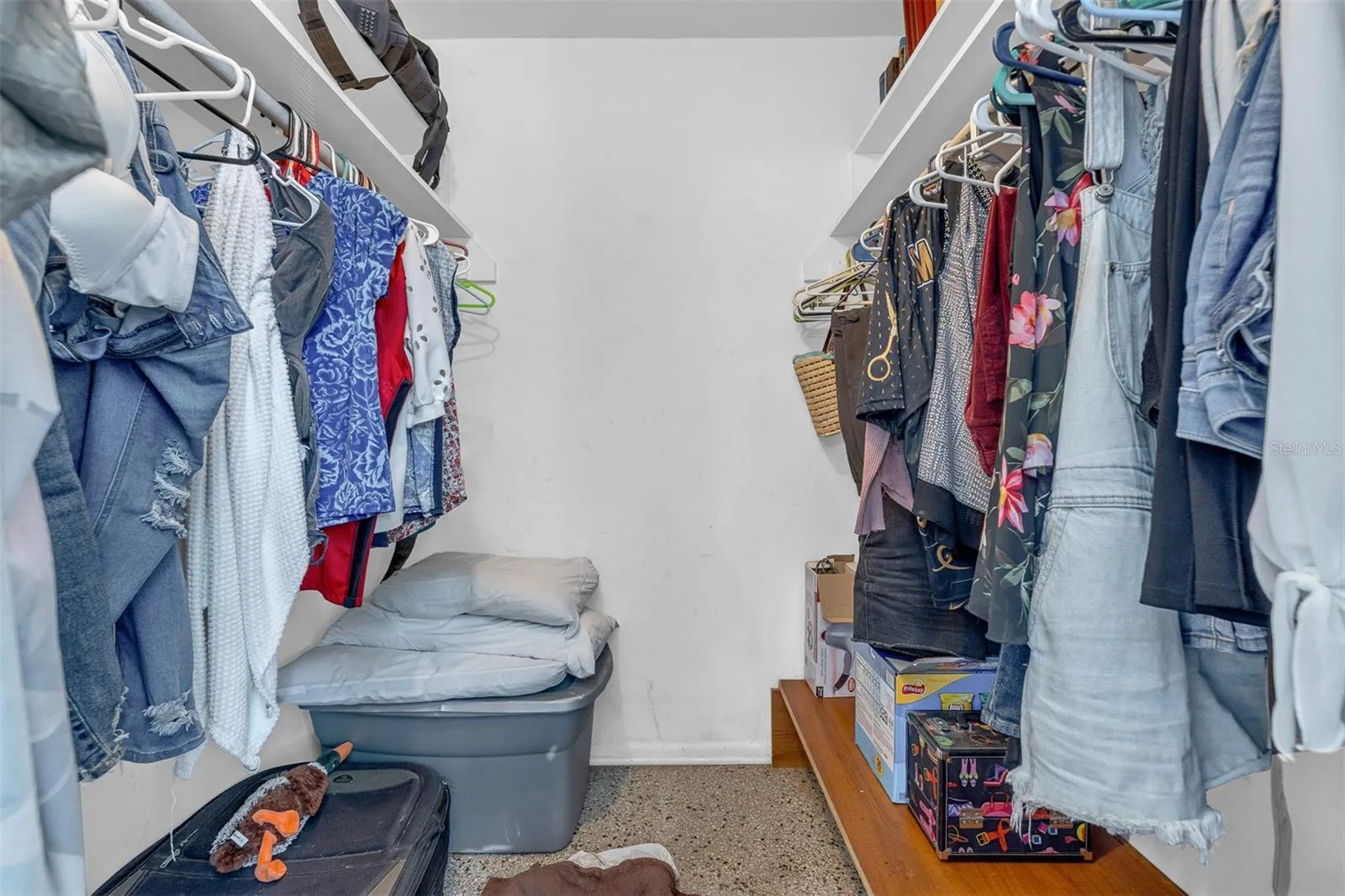 Walk-in closet with dual hanging sections, shelving, and floor-level storage.