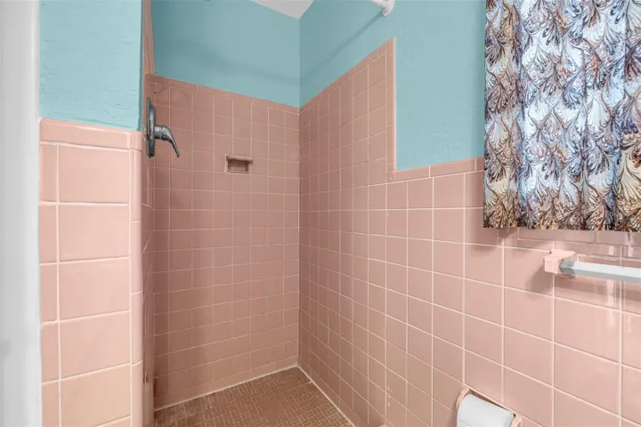 Shower area with vintage tile surround, built-in soap ledge, and overhead fixture.