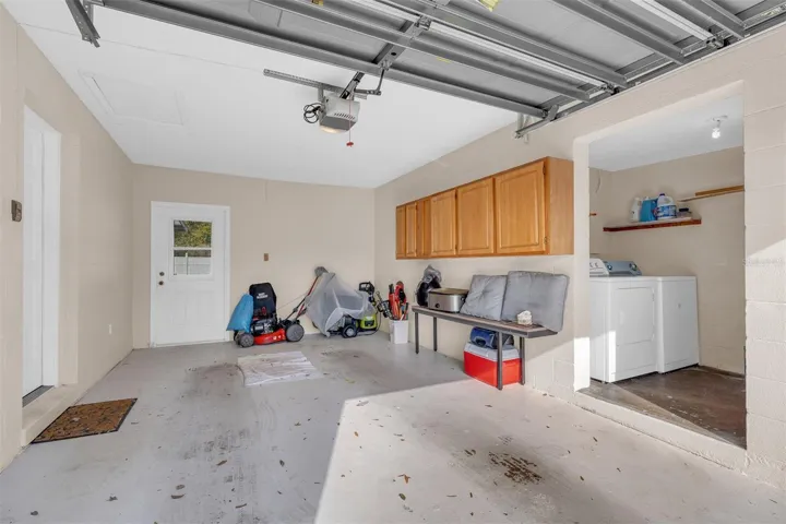 Garage with overhead door, storage cabinets, and laundry area.