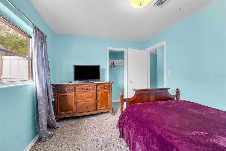 Bedroom angle showing dresser with TV, closet access, and natural light.