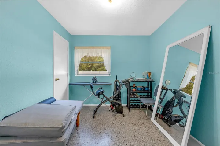 Flex room with exercise equipment, shelving, and full-length mirror.