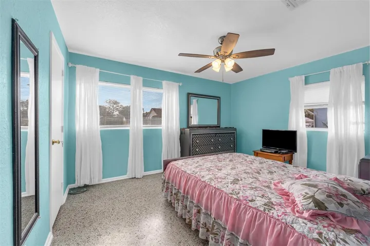 Bedroom with direct access to the bathroom. Features dresser storage, full-length mirror, and natural light from two windows.