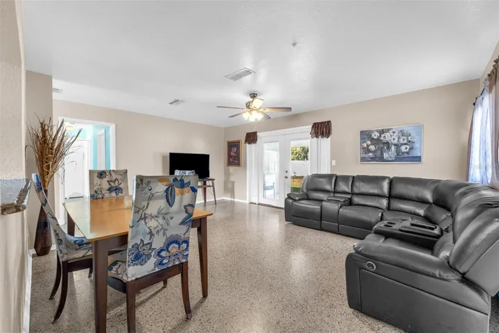 Spacious living area with sectional seating, ceiling fan, and entertainment wall. French doors offer access to the rear or bonus room.